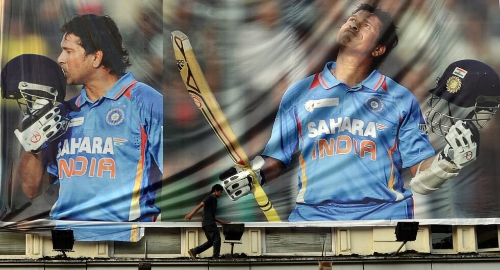 An Indian walks past a Sachin Tendulkar poster, 2013
