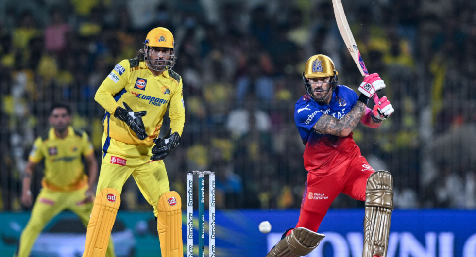 Royal Challengers Bangalore's captain Faf du Plessis plays a shot as Chennai Super Kings' MS Dhoni (L) watches during the Indian Premier League (IPL) Twenty20 cricket match between Chennai Super Kings and Royal Challengers Bangalore at the MA Chidambaram Stadium in Chennai on March 22, 2024.